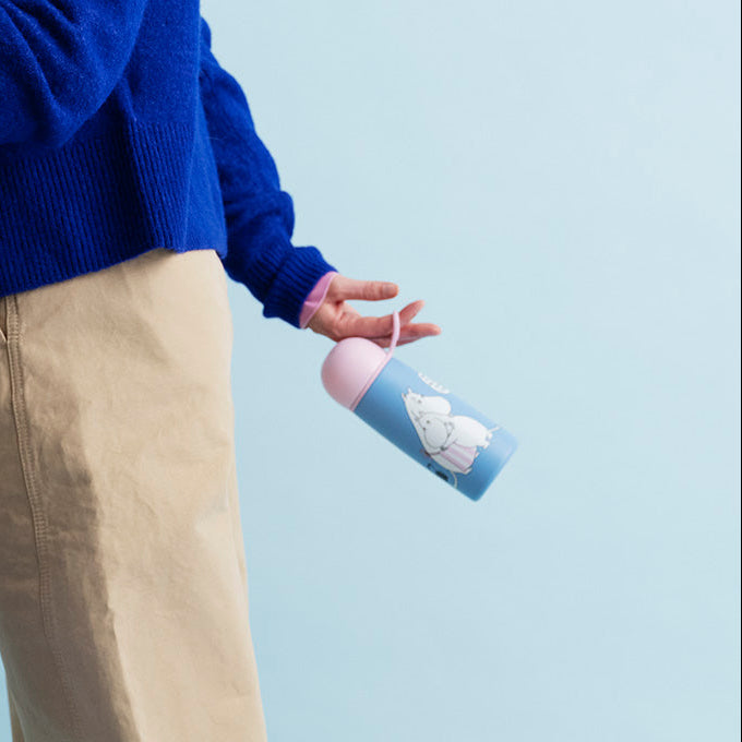 Person holding a tote bag with a scenic design against a light blue background