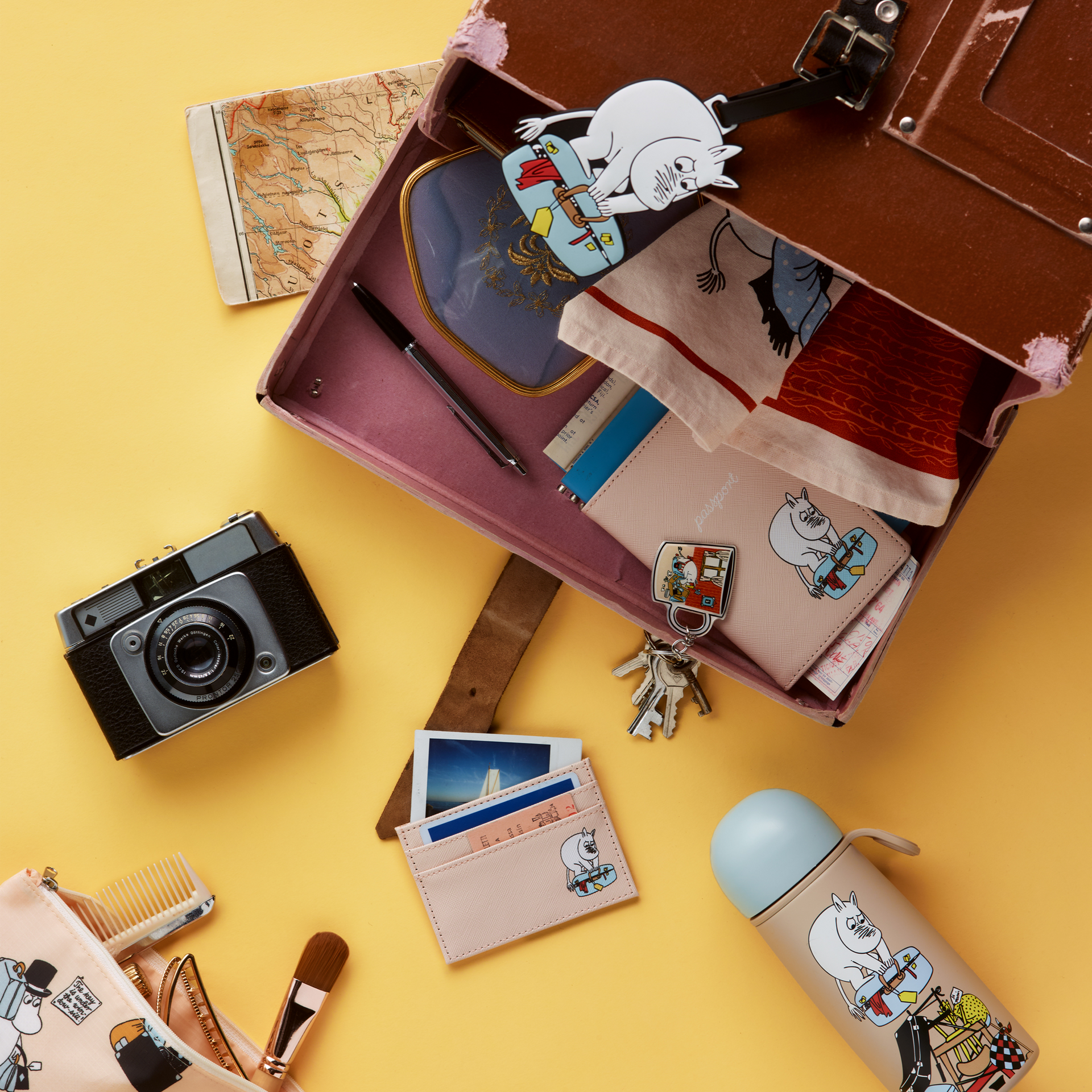 Mummi kortholder Ferieklar - Collection of Holiday Rush travel items items including a card holder, passport holder and thermos bottle on a yellow background.