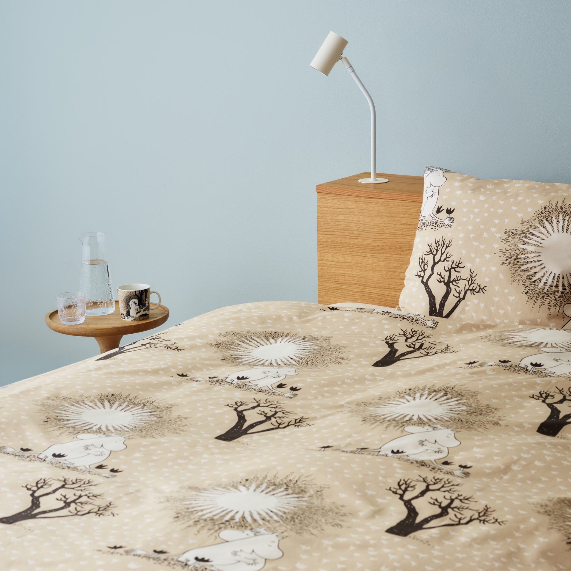 A bed set with the Love Beige bed linen and a wooden side tablle with the Love Beige mug.