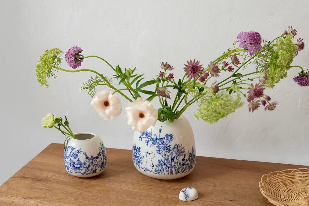 Two small ceramic Haru vases with decorative blue designs on a wooden surface against a plain background
