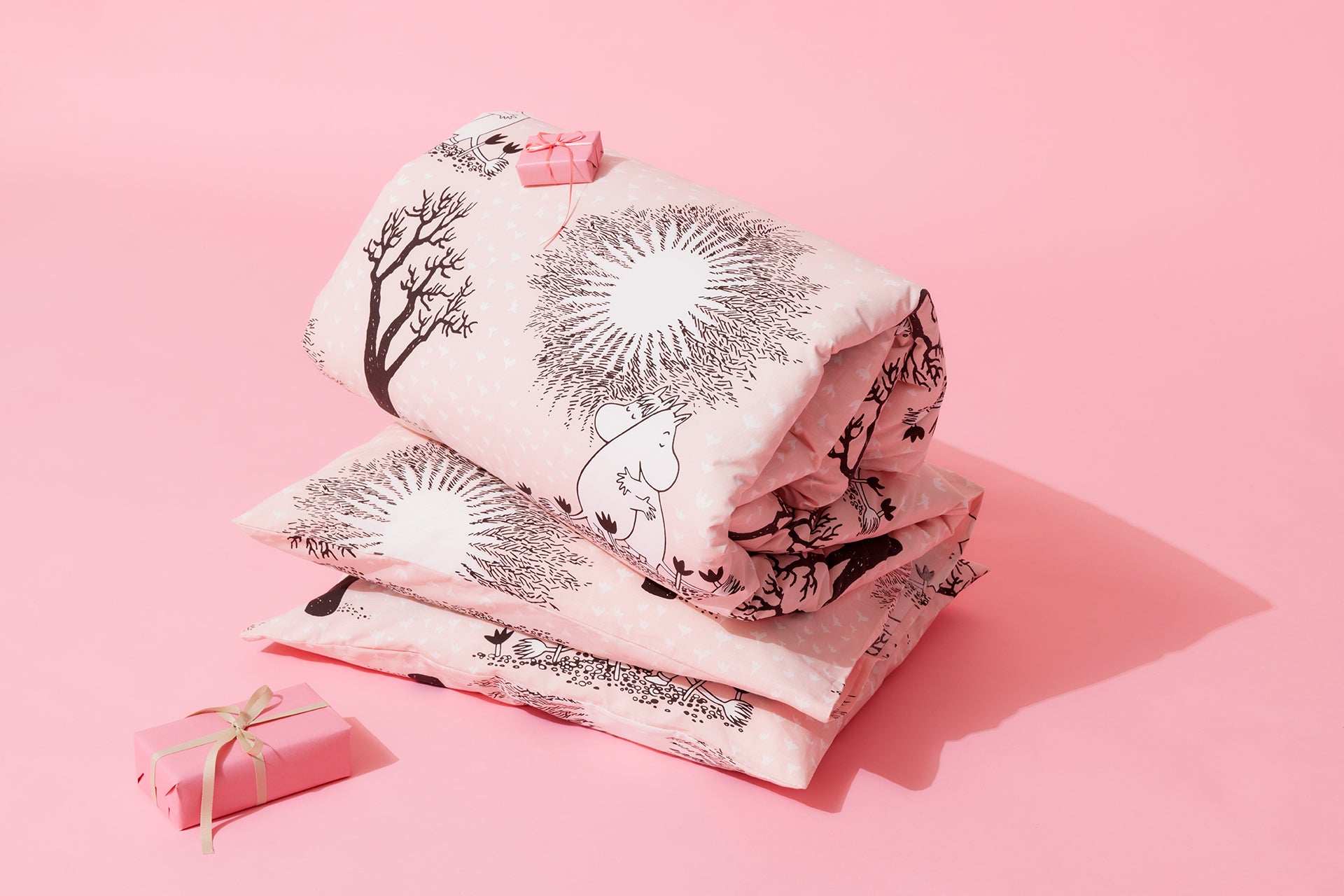 Moomin love duvet covers and a wrapped gift on a pink background