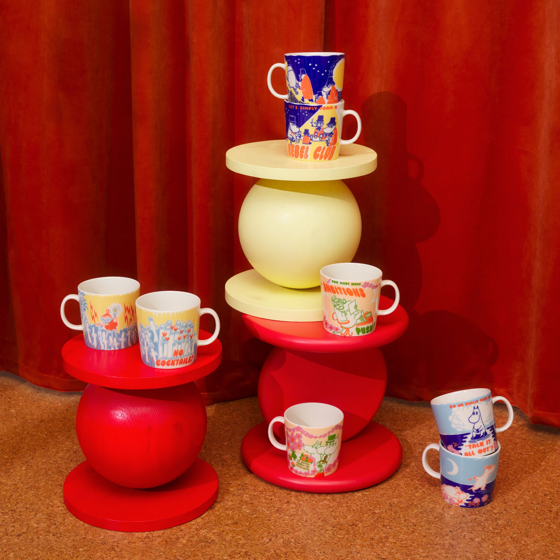 Rebel Club mugs on a tiered stand against a red curtain background