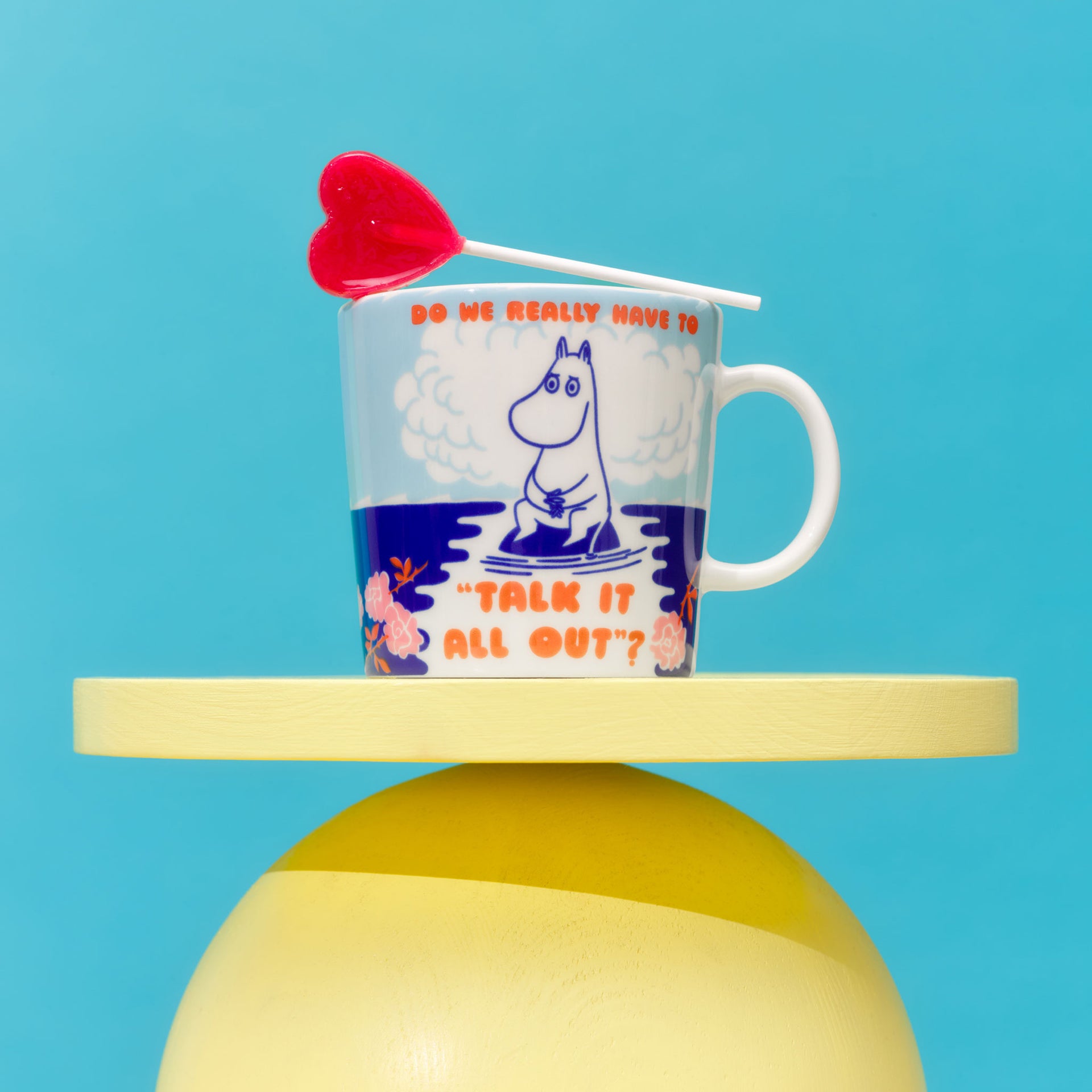 Talk It All Out mug on a yellow platform against a blue background