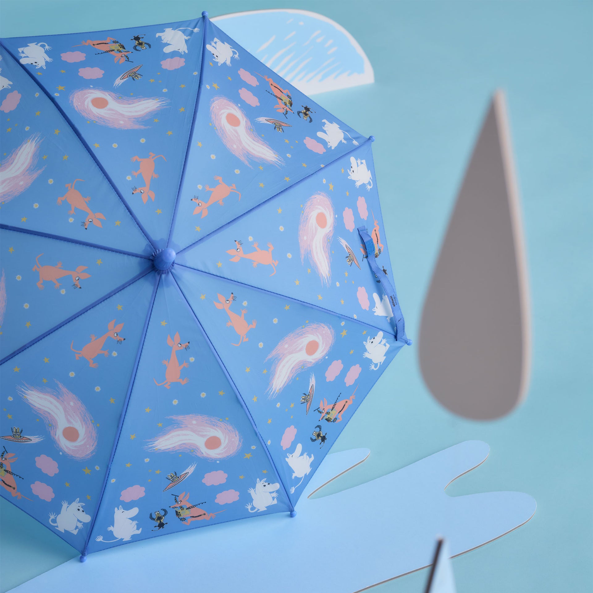 Mumin barn paraply Rymdäventyr - A light blue umbrella with the Space Adventure illustration on a light blue background with paper cutout props.