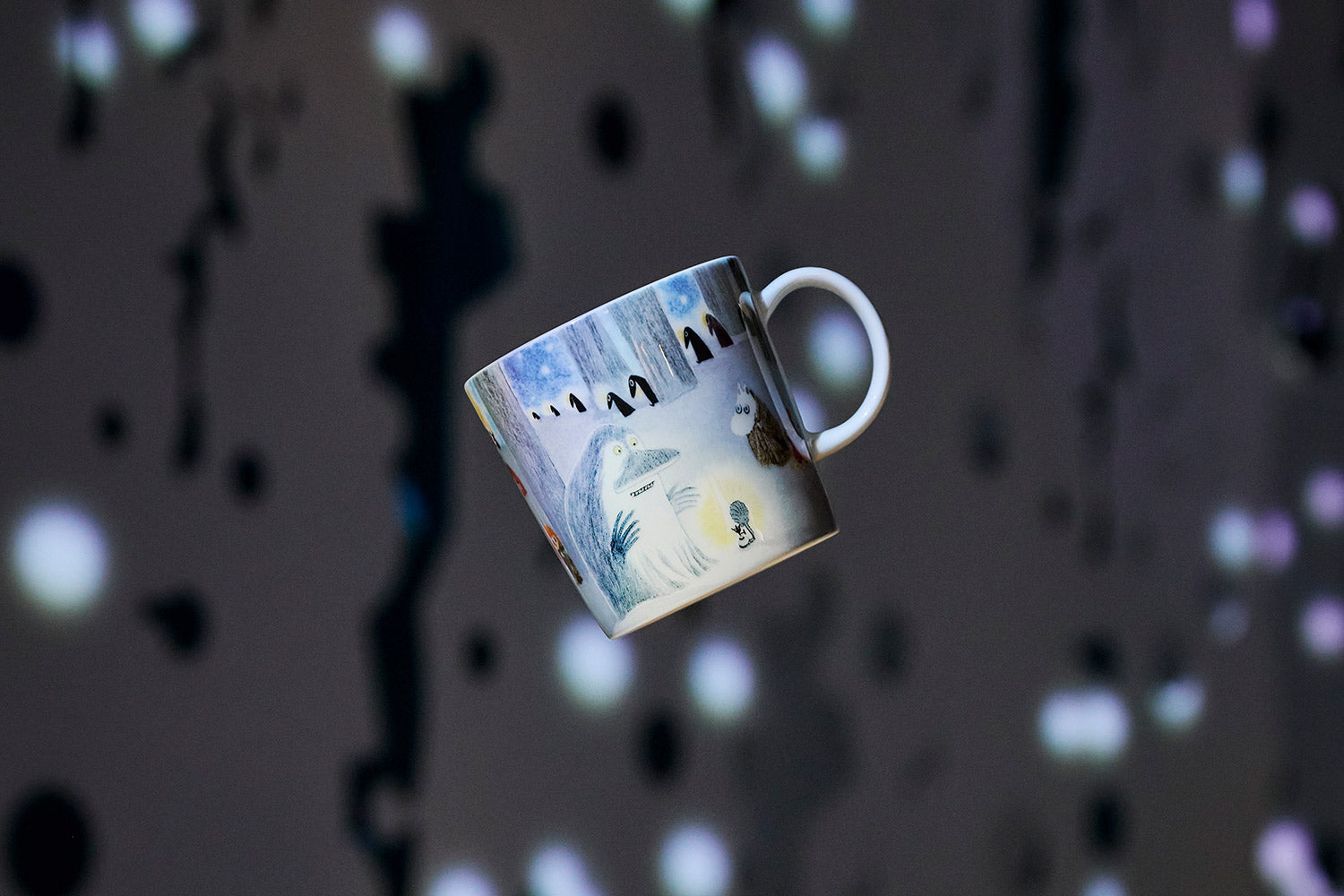 A ceramic Winternight Glow mug , shown floating against a dark background with bokeh light spots.