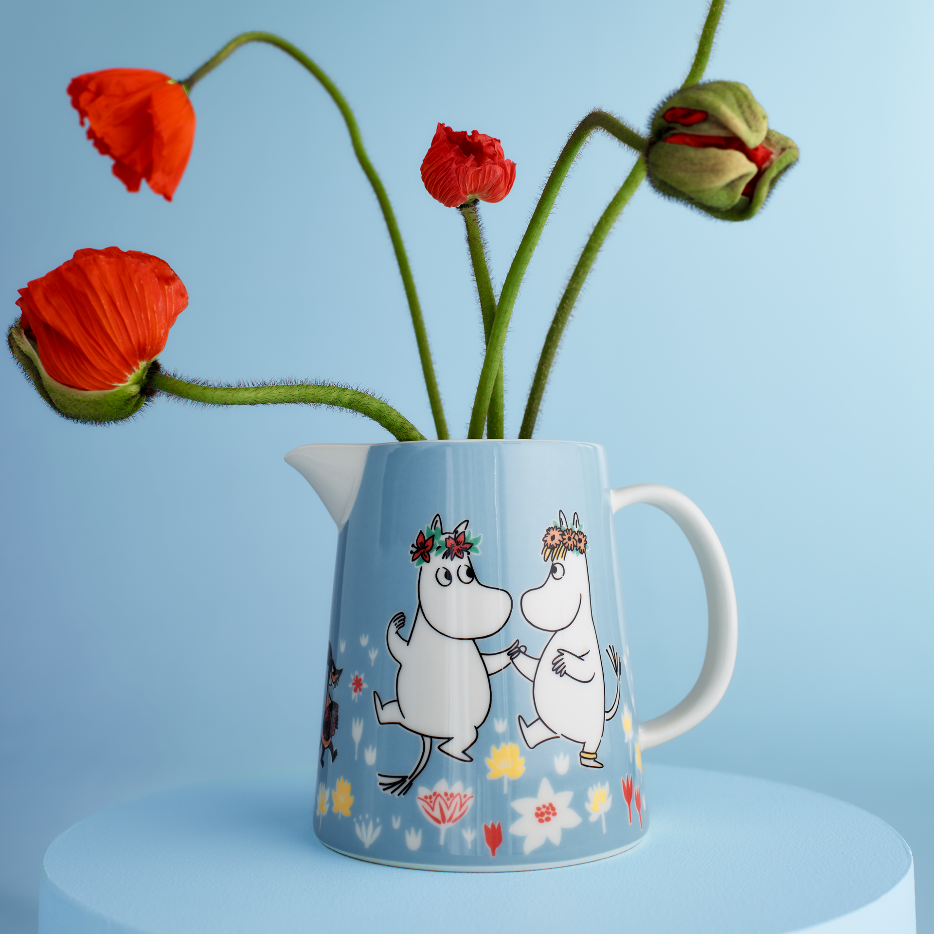 Mumin kan 1L Sommardans - Summer Dance pitcher containing red poppies on a light blue background