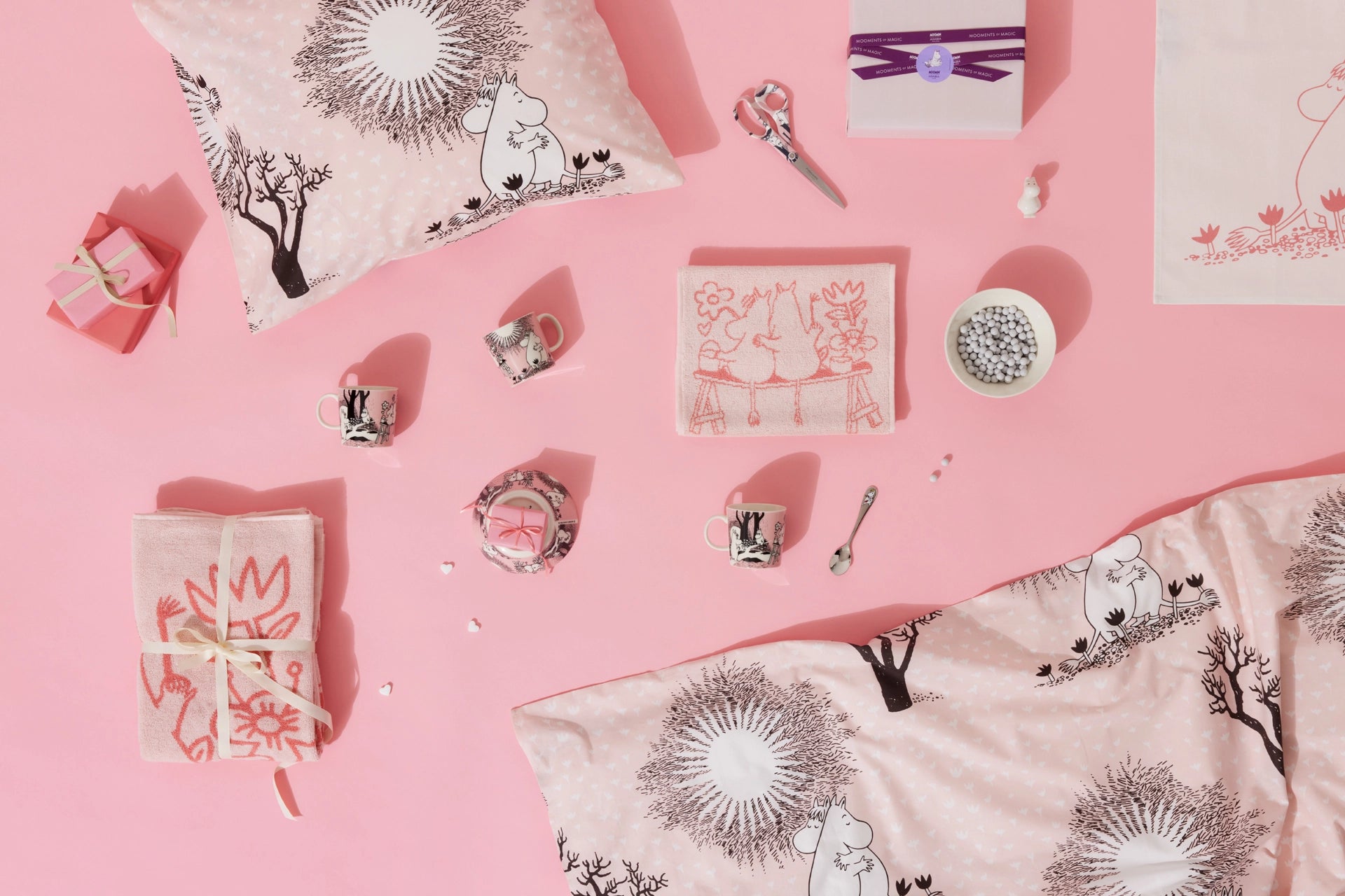 Decorative Moomin Love pillows and items on a pink background