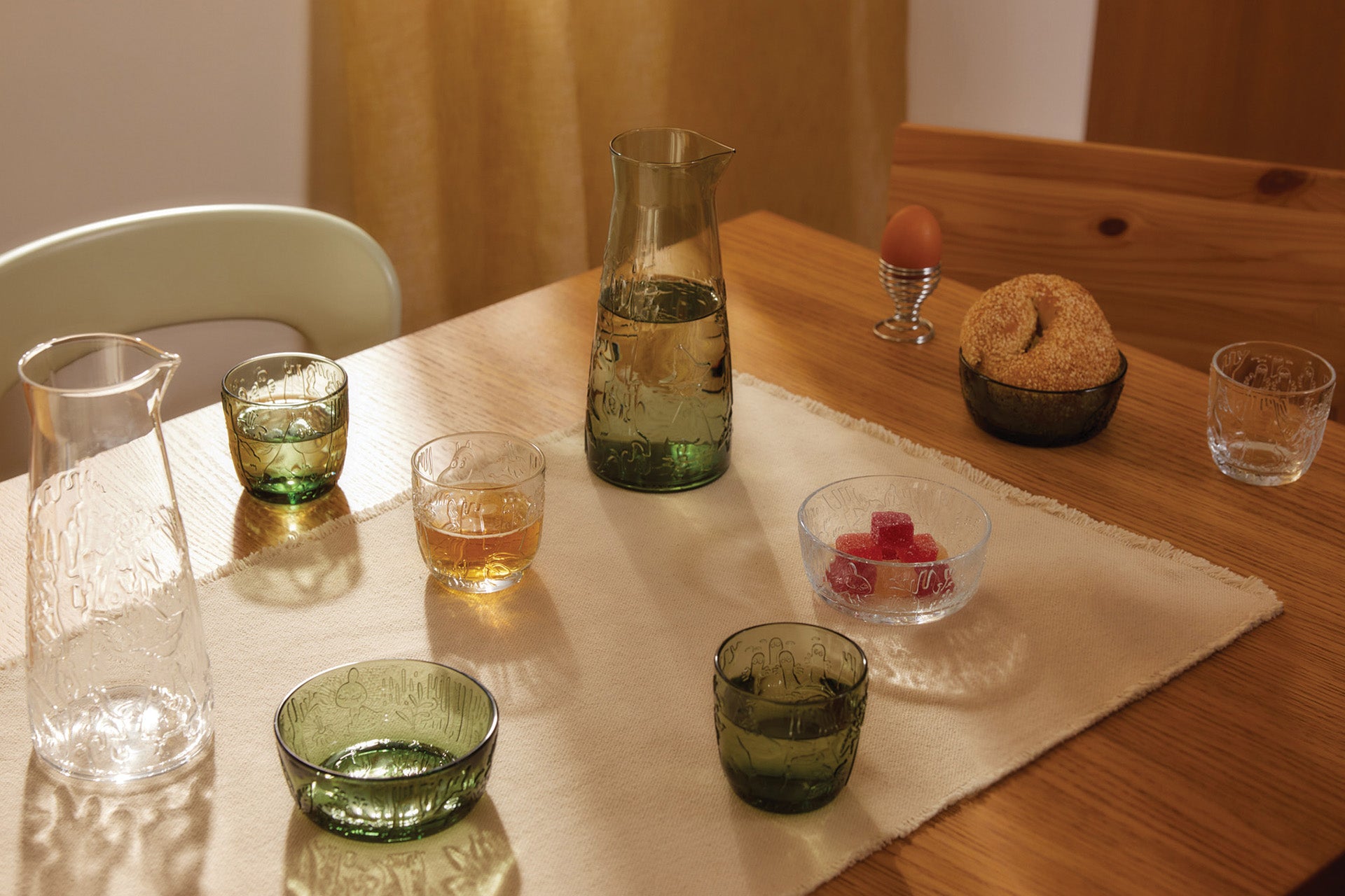 Table setting with Mystical forest glassware and a pitcher on a wooden table.