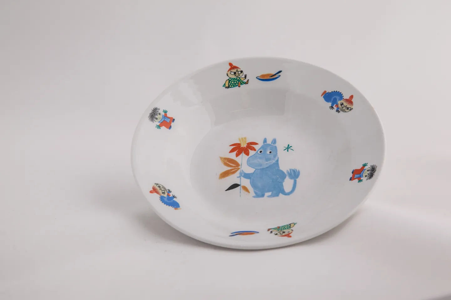 White deep plate with colorful moomin characters on a white background