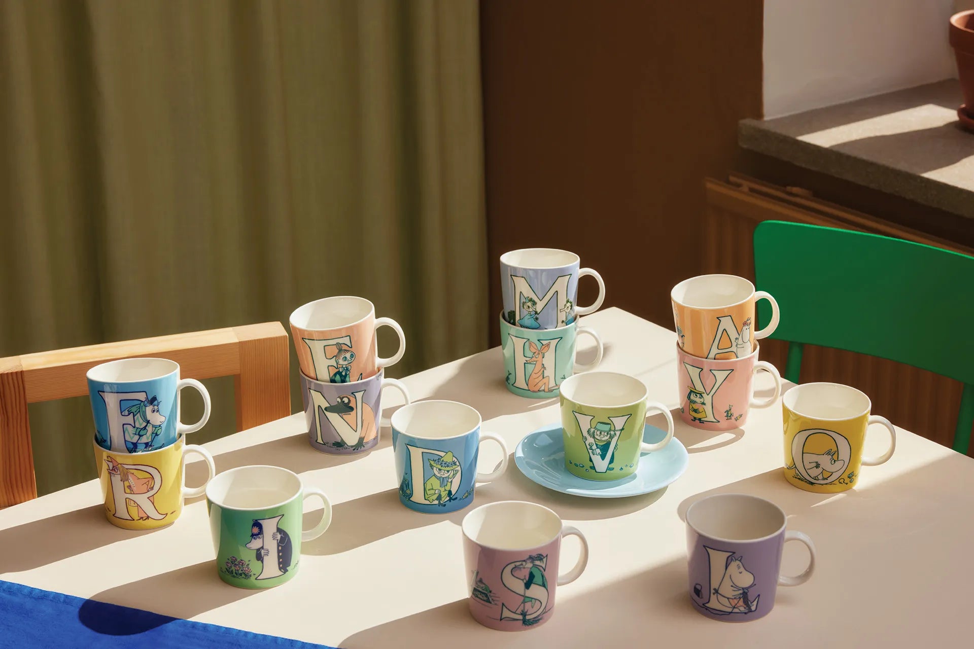 Colorful Moomin Arabia alphabet mugs with various designs on a table