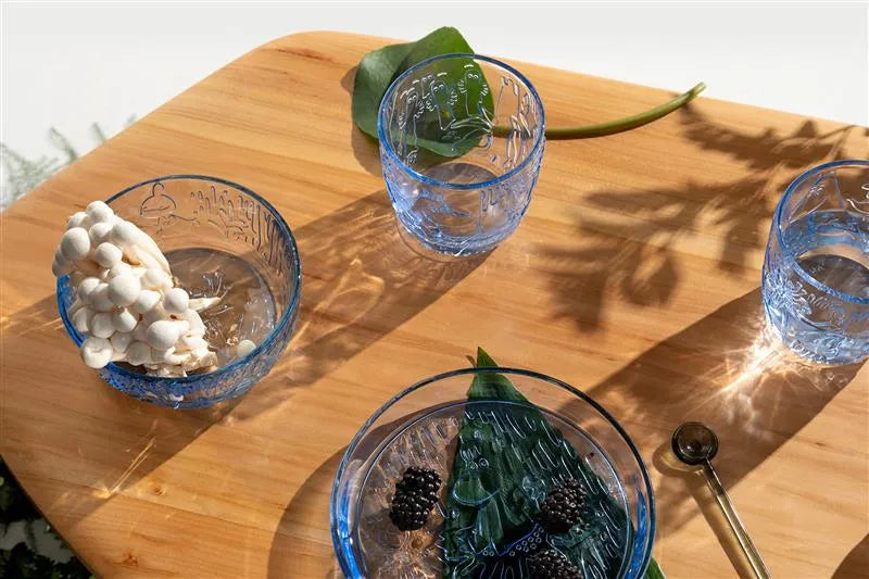 Three blue glass bowls with mystical forest decoration on a wooden surface