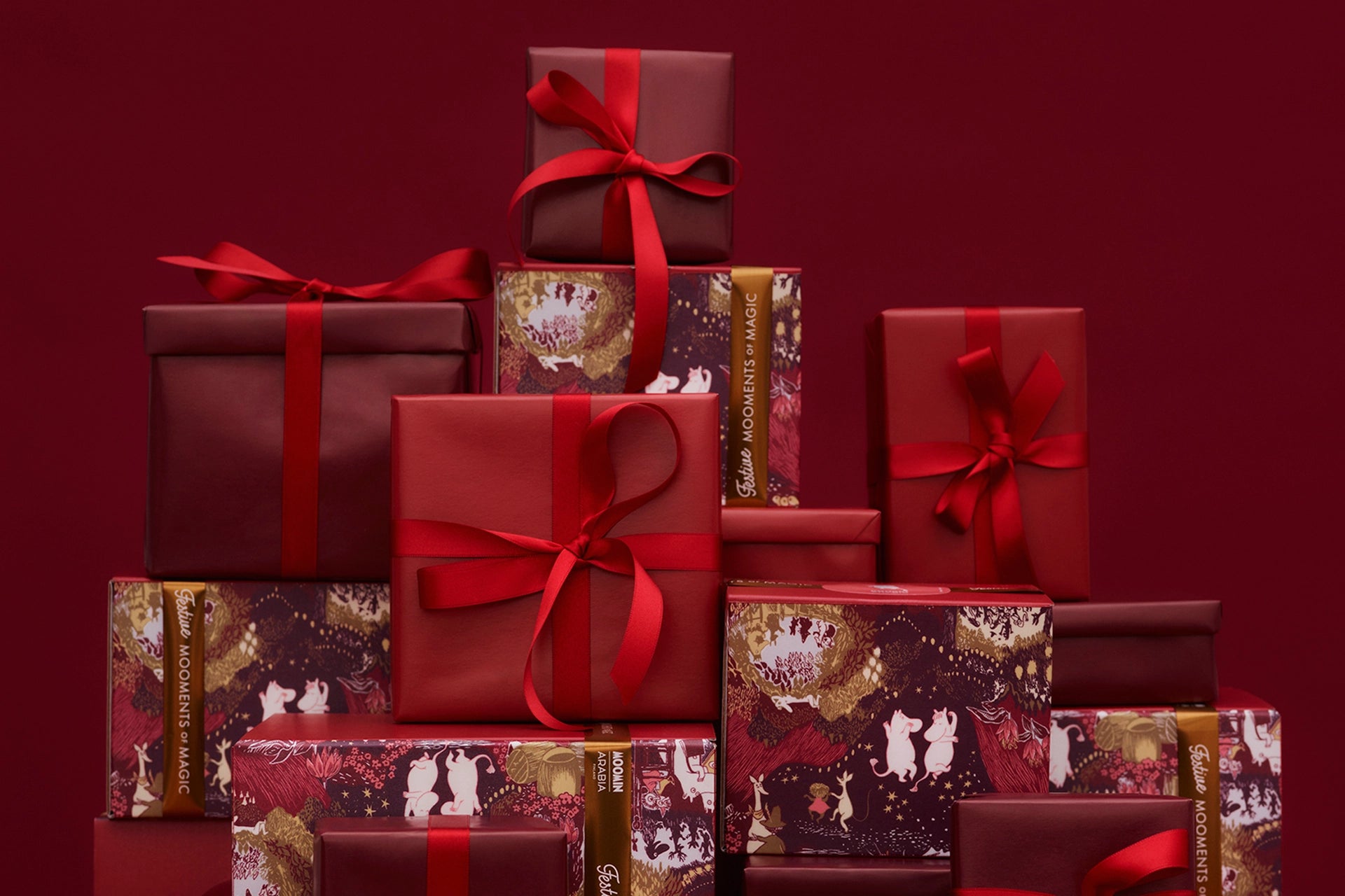 Stack of red gift boxes with ribbons, some with festive moments design on a red background