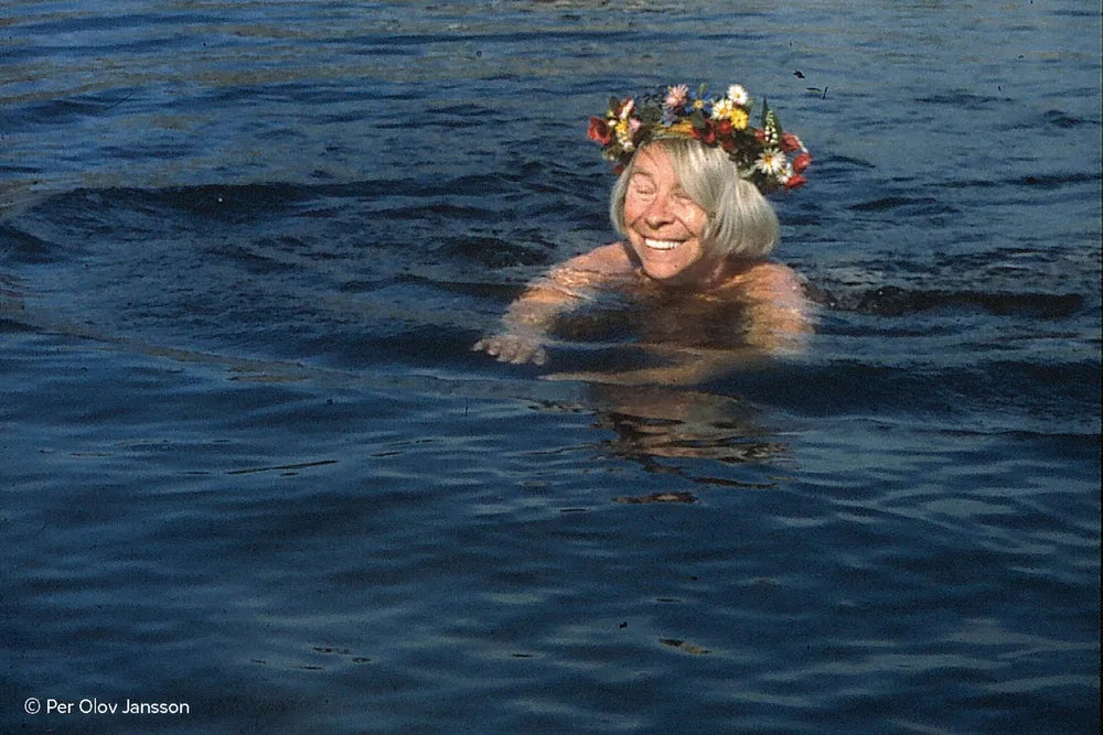 Tove Jansson swimming in water wearing a floral headband, image by Per Olov Jansson